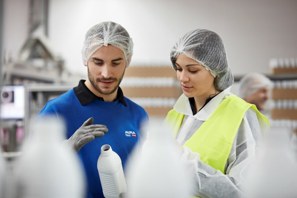 ALPLA Mitarbeiter begutachten eine frisch produzierte Flasche.