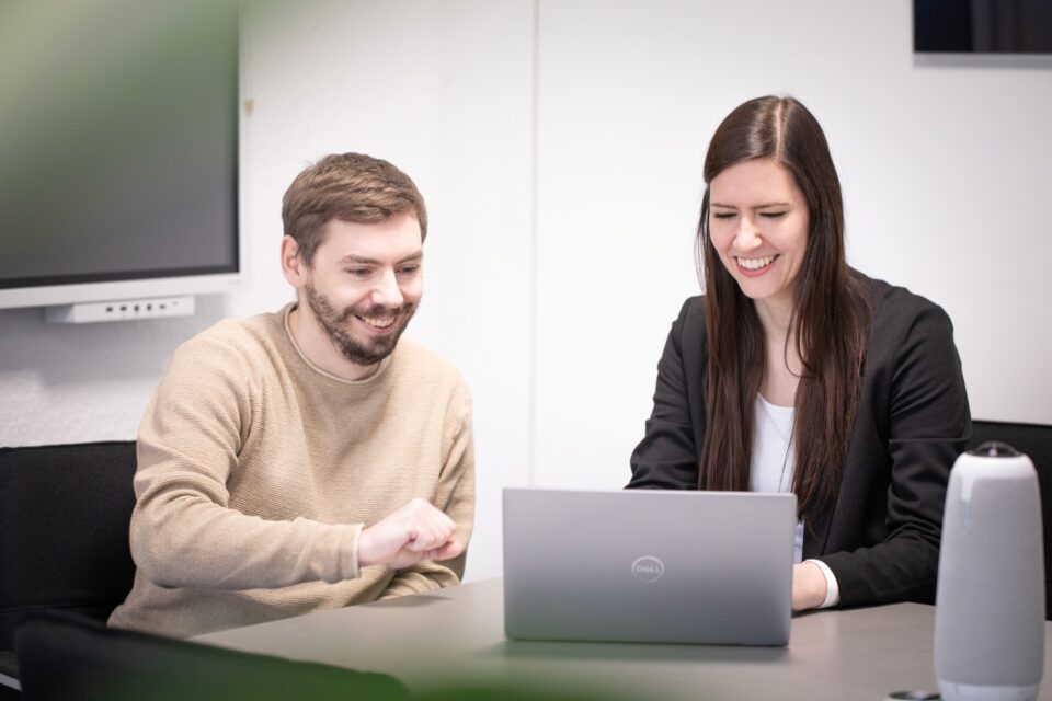 Mitarbeitende von Takko Fashion arbeiten gemeinsam am Laptop. 