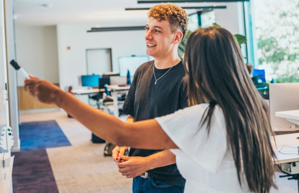 Mitarbeitende diskutieren vor Whiteboard